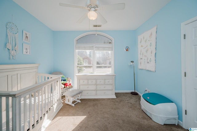 carpeted bedroom with a nursery area and ceiling fan