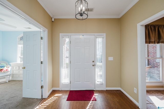 foyer entrance with crown molding, a notable chandelier, and hardwood / wood-style flooring