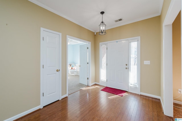 foyer with crown molding, a notable chandelier, and hardwood / wood-style flooring