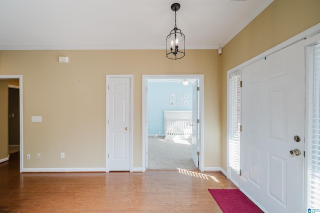 entrance foyer with an inviting chandelier, hardwood / wood-style floors, and ornamental molding