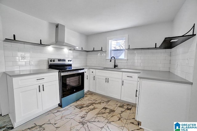 kitchen featuring tasteful backsplash, sink, white cabinets, stainless steel range with electric stovetop, and wall chimney range hood