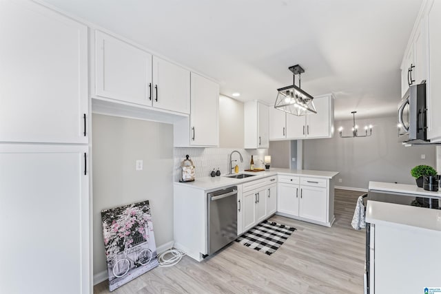 kitchen with sink, hanging light fixtures, appliances with stainless steel finishes, kitchen peninsula, and white cabinets