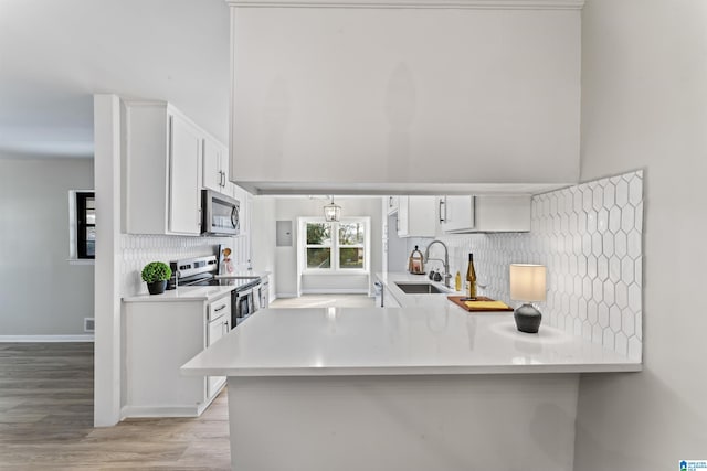 kitchen featuring white cabinetry, sink, kitchen peninsula, and appliances with stainless steel finishes