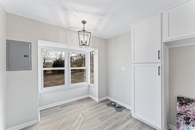 unfurnished dining area featuring a chandelier, electric panel, and light hardwood / wood-style flooring