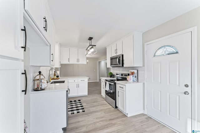 kitchen featuring sink, white cabinetry, stainless steel appliances, light hardwood / wood-style floors, and decorative backsplash