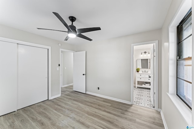 unfurnished bedroom with light hardwood / wood-style flooring, a closet, ceiling fan, and ensuite bathroom