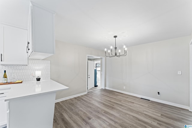 unfurnished dining area with a notable chandelier and light wood-type flooring