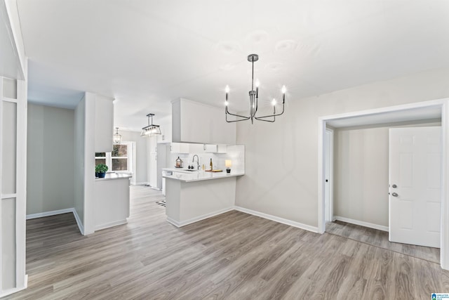 interior space featuring sink, white cabinets, an inviting chandelier, and kitchen peninsula