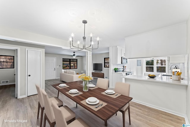 dining room featuring sink, ceiling fan with notable chandelier, and light wood-type flooring