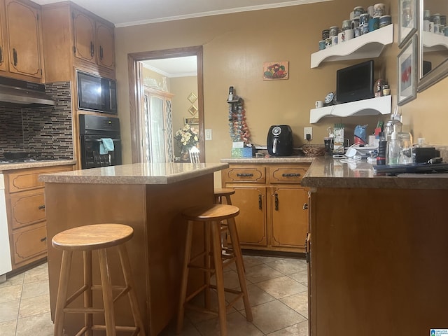 kitchen with a breakfast bar area, backsplash, ornamental molding, black appliances, and light tile patterned flooring