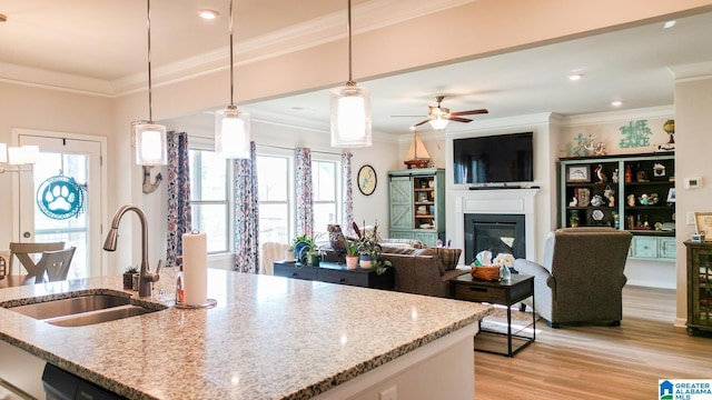 kitchen with sink, decorative light fixtures, ornamental molding, and light stone countertops