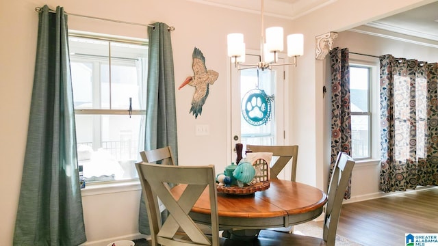 dining space with crown molding, wood-type flooring, and an inviting chandelier