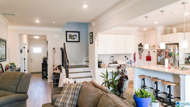 kitchen featuring pendant lighting, white cabinetry, a kitchen island with sink, stainless steel refrigerator with ice dispenser, and light stone countertops