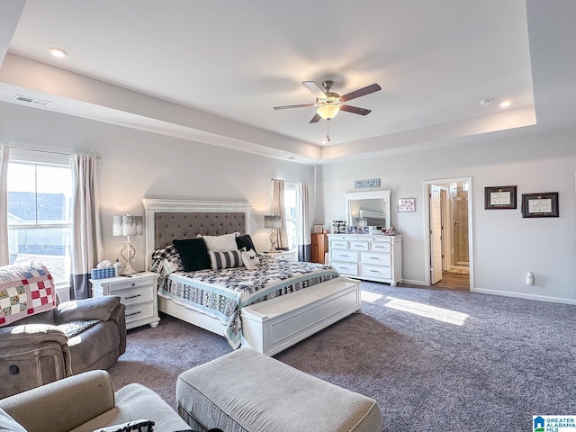 bedroom with dark colored carpet, ceiling fan, and a tray ceiling