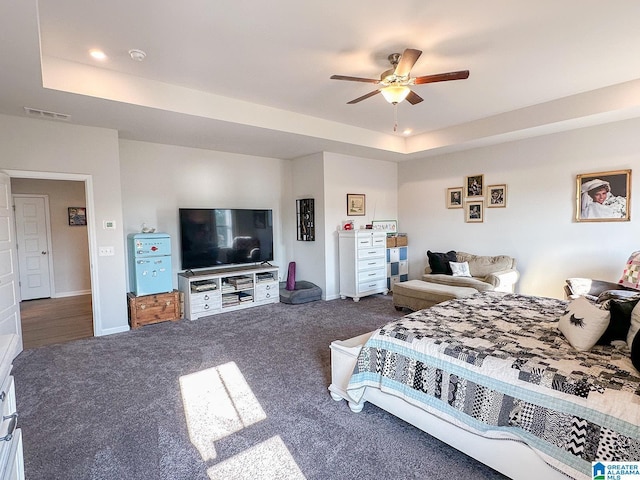 carpeted bedroom with ceiling fan and a raised ceiling