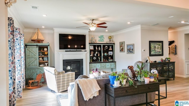 living room featuring ornamental molding, ceiling fan, and light wood-type flooring