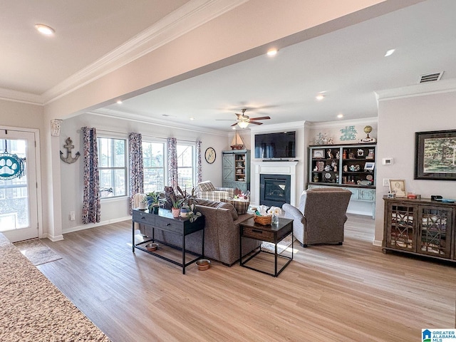 living room with light hardwood / wood-style flooring, ornamental molding, and ceiling fan