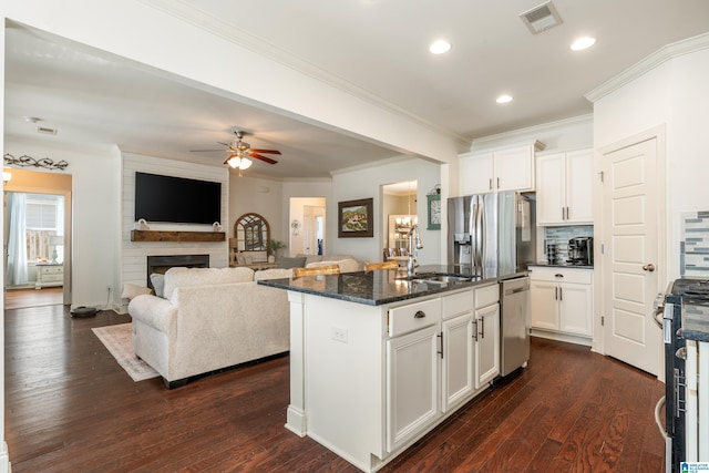 kitchen featuring sink, dark stone counters, stainless steel appliances, a kitchen island with sink, and white cabinets