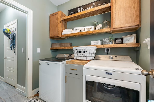 clothes washing area with cabinets and washing machine and clothes dryer