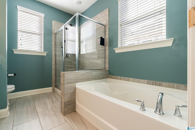 bathroom with independent shower and bath, a wealth of natural light, and toilet