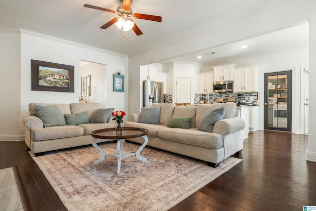 living room featuring dark wood-type flooring, ceiling fan, crown molding, and sink