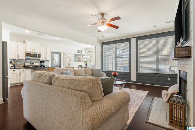 living room featuring crown molding, ceiling fan with notable chandelier, and dark hardwood / wood-style floors