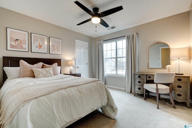 bedroom with ceiling fan, light colored carpet, and a textured ceiling