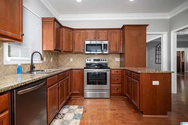 kitchen featuring stainless steel appliances, ornamental molding, sink, and light stone counters