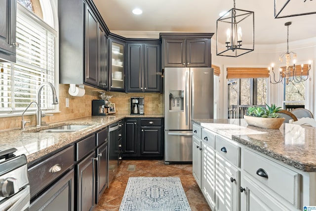 kitchen featuring sink, appliances with stainless steel finishes, tasteful backsplash, white cabinets, and a chandelier