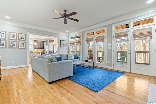 living room with ornamental molding, ceiling fan with notable chandelier, and light hardwood / wood-style flooring