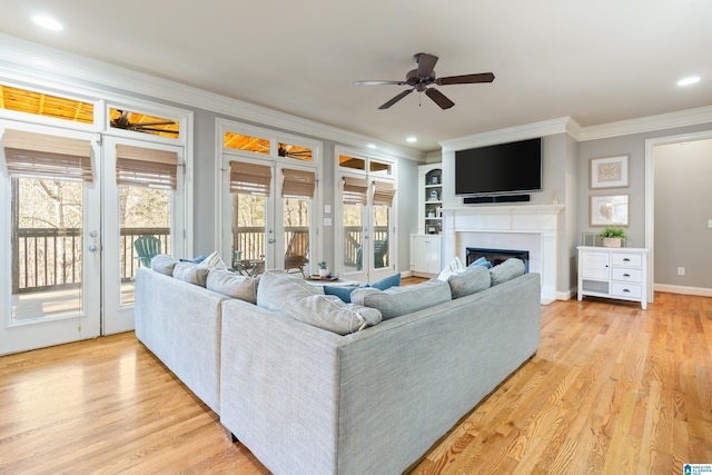 living room featuring ceiling fan, crown molding, a healthy amount of sunlight, and light wood-type flooring