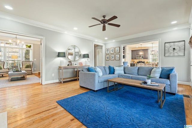 living room with ornamental molding, ceiling fan with notable chandelier, and hardwood / wood-style floors