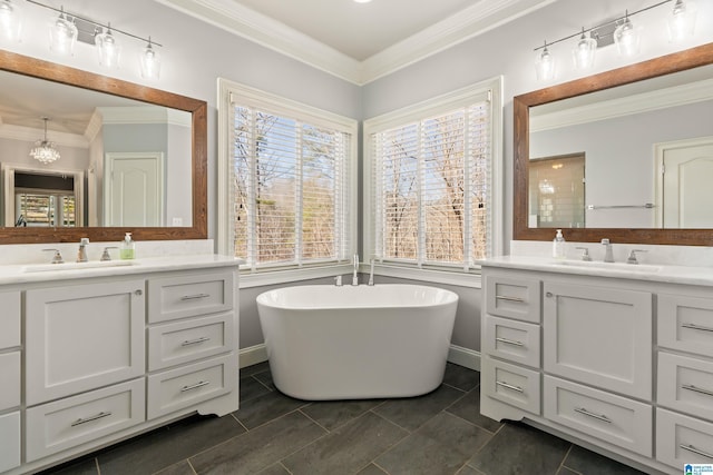 bathroom featuring a tub, vanity, crown molding, and a wealth of natural light