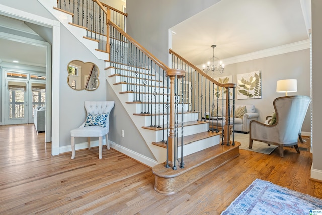 stairway featuring hardwood / wood-style floors, crown molding, and a notable chandelier