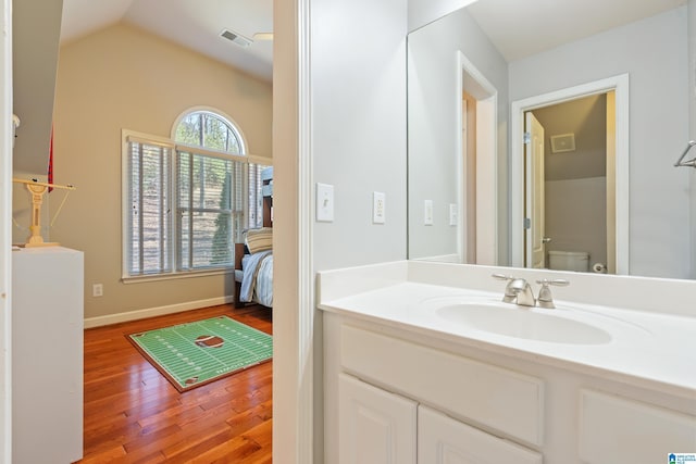 bathroom with vaulted ceiling, vanity, toilet, and hardwood / wood-style floors