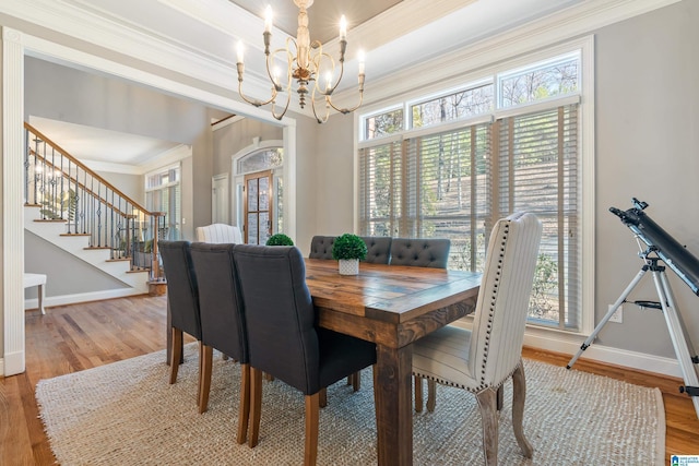 dining area with crown molding, wood-type flooring, a chandelier, and plenty of natural light