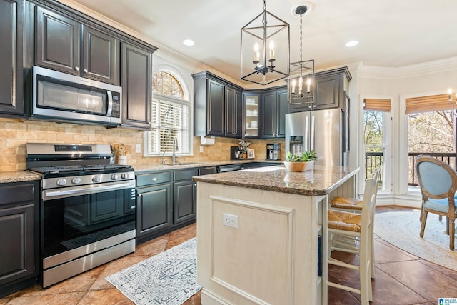 kitchen featuring sink, a kitchen island, stainless steel appliances, light stone countertops, and backsplash