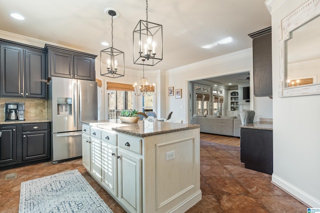 kitchen with stainless steel refrigerator with ice dispenser, tasteful backsplash, hanging light fixtures, a kitchen island, and light stone countertops