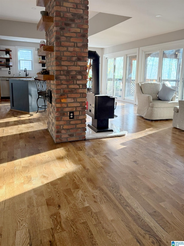 unfurnished living room featuring a wealth of natural light, light wood-type flooring, and a wood stove