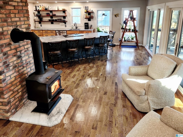 living room with sink, hardwood / wood-style floors, and a wood stove