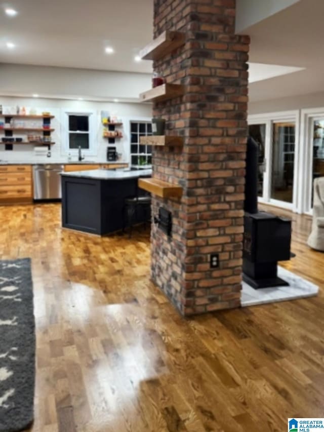 kitchen with hardwood / wood-style floors, dishwasher, and a wood stove