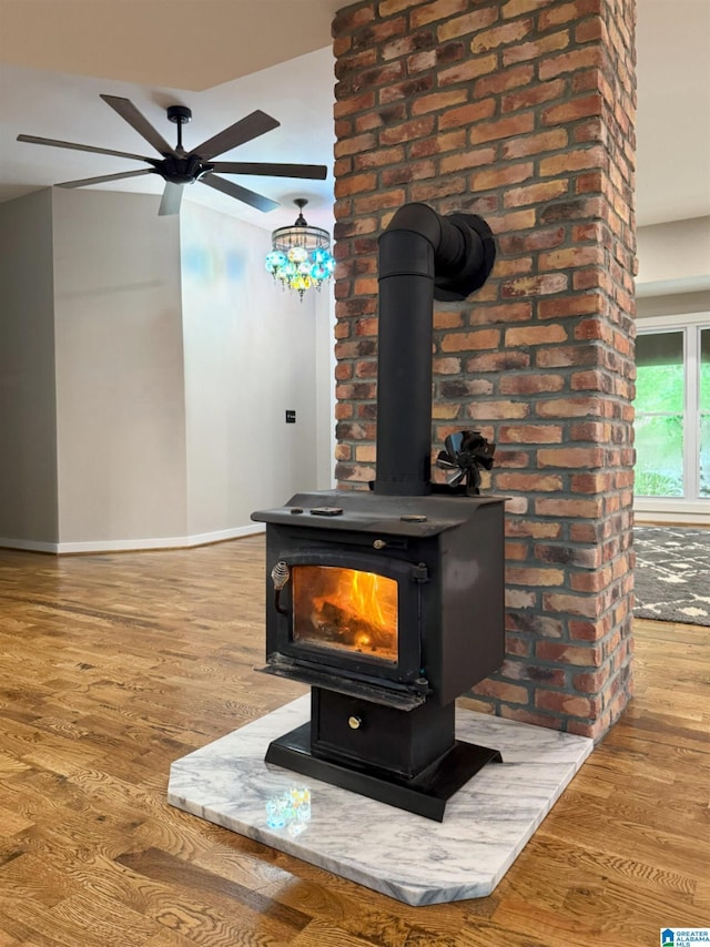 room details with hardwood / wood-style floors, ceiling fan, and a wood stove