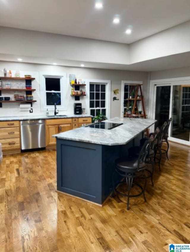 kitchen with sink, a center island, black electric stovetop, stainless steel dishwasher, and light hardwood / wood-style floors