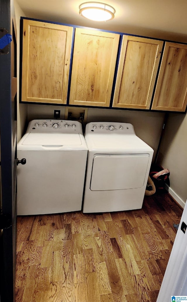 laundry area with hardwood / wood-style flooring, washing machine and dryer, and cabinets