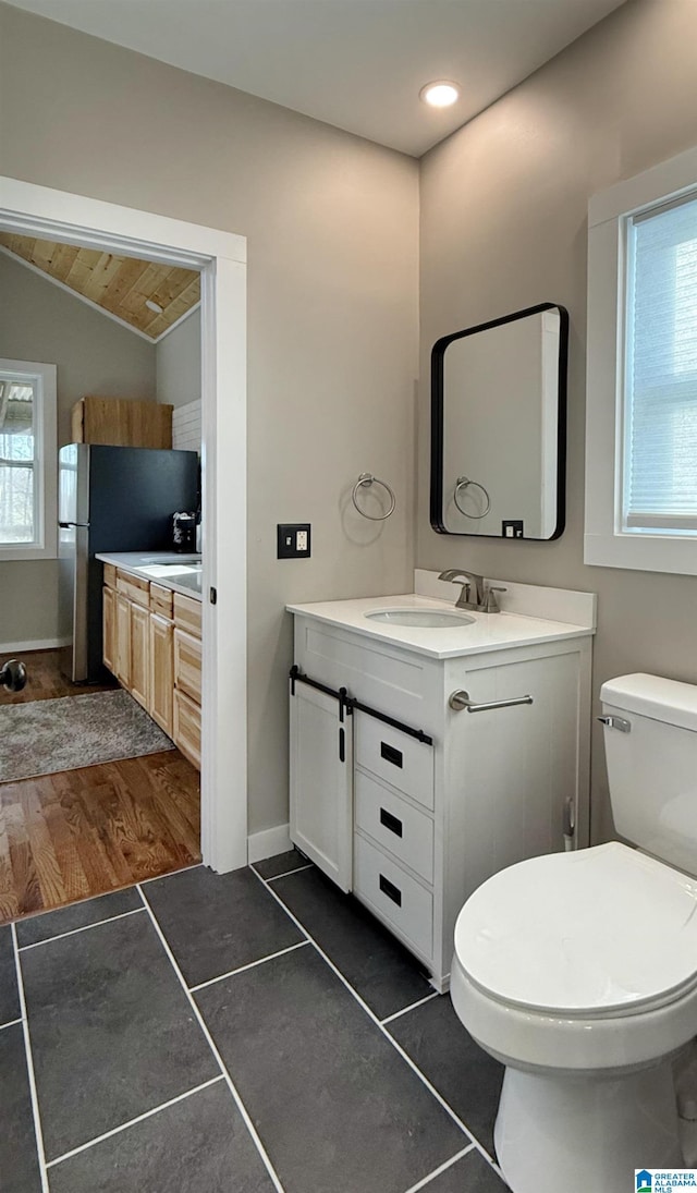 bathroom with vanity, lofted ceiling, and toilet