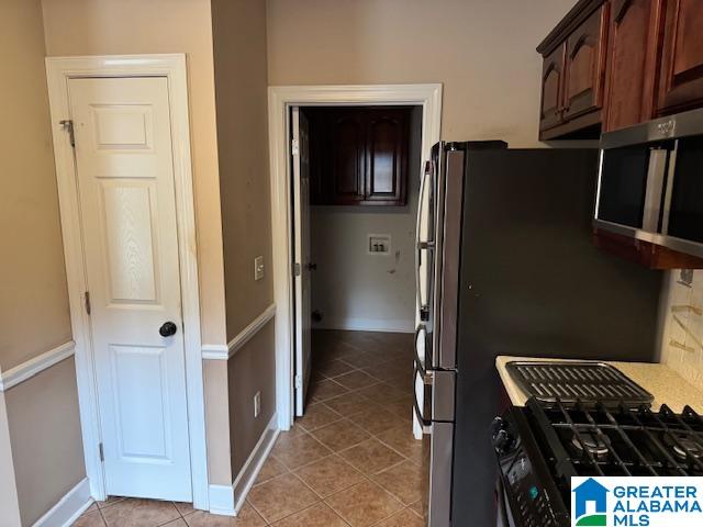 kitchen with backsplash, dark brown cabinetry, gas range oven, and light tile patterned floors