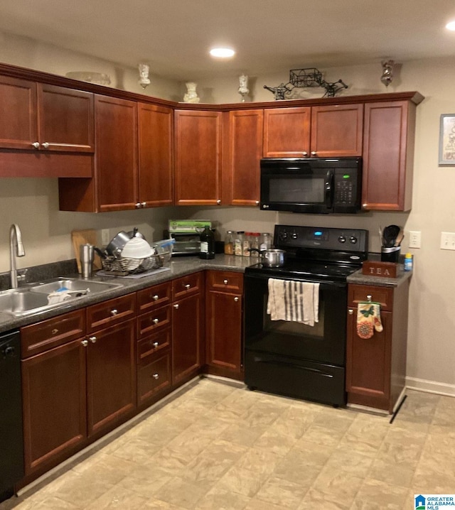 kitchen with dark countertops, black appliances, baseboards, and a sink