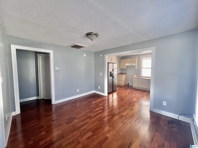 unfurnished living room with dark wood-type flooring and a textured ceiling