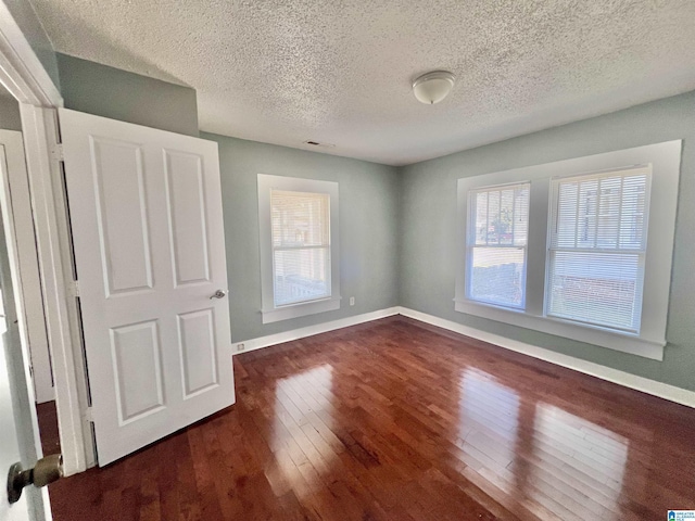 spare room featuring dark wood-type flooring and a textured ceiling