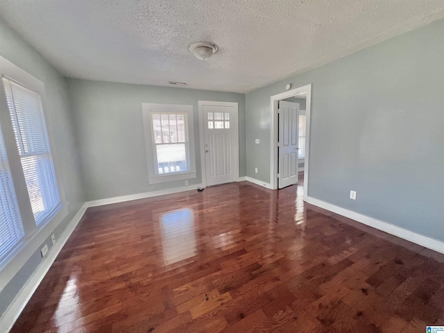 foyer entrance with dark wood-type flooring and a textured ceiling